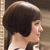 Pixelated profile view of a person with short dark hair and light skin, wearing a light-colored top against a muted background.