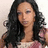 A pixelated image of a person with long dark hair wearing a patterned top, set against a light background.