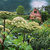 Pixelated static image shows a landscape with green fields, trees, and a red-roofed house under a blue sky.