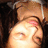 Pixelated close-up of a person's face with closed eyes, light skin, and dark hair, set against a dark background with a light-colored object above the head.
