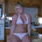 Pixelated image of a person in white lingerie standing indoors with blurred background elements.