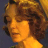 Pixelated close-up of a person with curly brown hair and warm-toned skin, set against a dark blue background.