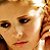 Pixelated close-up of a person's face with light brown hair, dark eyes, and reddish lips against warm-toned background.