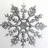 Static pixelated snowflake with six symmetrical arms, rendered in grayscale tones on a light background.