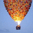 A hot air balloon with a flame at its base floats against a light blue sky, while green text on yellow background reads "Nothing is impossible just believe in whatever it is".