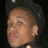 Pixelated close-up of a person's face with short dark hair, light skin tone, and closed eyes against a dark background.