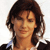 Pixelated image of a person with shoulder-length brown hair, closed eyes, and a neutral expression wearing a dark jacket over a light shirt against a white background.