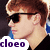 Pixelated image of a person with light brown hair and dark sunglasses, wearing black clothing against a blue background.