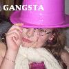 A person wearing a large pink top hat, white scarf, and pink top with hand near face, with 'GANGSTA' text above.