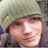 Pixelated image of a person wearing a light-colored knit hat with visible texture, positioned next to bright pink text on black background.