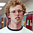 Pixelated image of a person with curly light brown hair wearing glasses and a white shirt, next to blue background with text.