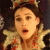 A pixelated close-up of a person wearing a golden crown with red accents and a gold and red patterned garment, mouth open in a surprised expression.