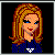 Pixelated character with orange-blonde hair, blue eyes, red lips wearing a dark blue top with white symbol and gray pants.