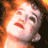 Pixelated static image of a person's face with fiery orange and brown background elements, likely from a movie or theatrical performance context.