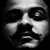 Pixelated grayscale face with asymmetrical features, one eye closed and the other open, mouth slightly downturned in a neutral expression.