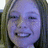 Pixelated close-up of a person's face with a wide smile, showing teeth, under purple-toned lighting against a dark background.