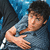 Pixelated image of a person with dark hair wearing a light blue shirt, extending an arm forward with an open hand against a blue and dark background.