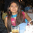 Pixelated image of a person with long brown hair wearing blue and pink clothing, holding an object against a dark background.