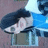 Pixelated static image of a figure with dark hair and light clothing against blue and gray background elements.