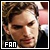 Pixelated close-up of a person with brown hair and light skin, wearing dark clothing, with the word FAN in white block letters at bottom left.