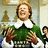 Pixelated image of a person with light brown hair wearing a green sweater over a white collared shirt, standing in front of an indistinct background.