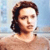 Pixelated image of a person with shoulder-length brown hair against a light blue and beige background.