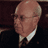 Static 48x48 pixel buddy icon showing a close-up of an older man's face with glasses, light skin tone, and formal attire against dark background.