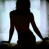 Silhouette of a person standing with arms slightly extended, back facing viewer, against light blue and white gradient background.