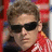 A pixelated image of a person wearing dark sunglasses and a red-and-white striped shirt, with red and gray background sections containing stylized text.