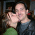 A static image of two people in close embrace, one kissing the other's cheek against a dark background.