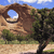 Pixelated landscape with natural rock formation, green vegetation, and blue sky background.