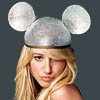 A person with long blonde hair wears a silver helmet with two large round ears against a dark gray background.