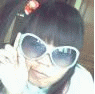 A person with dark hair and a red bow wears white heart-shaped sunglasses, making various facial expressions while holding the glasses.