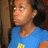 Pixelated close-up of a person in blue shirt with yellow symbol, side profile against dark background.