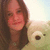 A person with long brown hair holds a light green teddy bear against a bright sky background, showing slight variations in pose and lighting across frames.