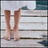 A pixelated static image shows two light brown boots standing on a striped surface with horizontal bands of white, gray, and dark blue.