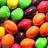 Pixelated image of colorful candy-coated chocolates with text overlays in pink pixel font on black background.