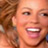 Pixelated close-up of a smiling person with light skin and brown hair, cropped to show face and partial shoulder in low-resolution static image.