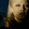 A sequence of animated frames showing a person with blonde hair, dark top, and silver cross necklace, transitioning from face to chest to hands holding a small object.