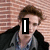 A person with brown hair in a black jacket and blue shirt stands against a brick wall, with text overlays changing across frames.