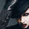 A person with pale skin, dark eye makeup, and red lips wears a black hat and textured clothing in four distinct poses against a gray background.