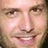 Pixelated close-up of a smiling person's face with visible eyes, nose, mouth, and skin tones in beige and brown hues.