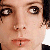 A pixelated close-up of a person's face showing eyes, nose, mouth, and part of the forehead with visible skin texture and dark hair on the right side.