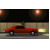 Animated sequence of a red classic car driving left to right across a nighttime urban street with illuminated streetlights and building facades.