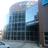 Pixelated static image of a modern building with reflective glass windows and a curved facade under a bright sky.