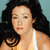 Pixelated image of a person with long dark hair wearing a light-colored sleeveless top against a light blue background.