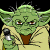Green-skinned character with large ears wears tan robe over brown shirt, holds green lightsaber in right hand against black background.