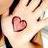 Pixelated static icon featuring a pink heart symbol on a light background with dark brown or black curved lines resembling hair, possibly part of a character's face.