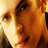 Pixelated close-up of a person's face with warm orange and brown tones, showing partial facial features including eyes, nose, and mouth against a light background.