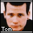 Static 48x48 pixel buddy icon featuring a close-up of a person's face with dark hair and light skin, set against a black background with white borders, labeled "Tom" in blocky text at the bottom left.